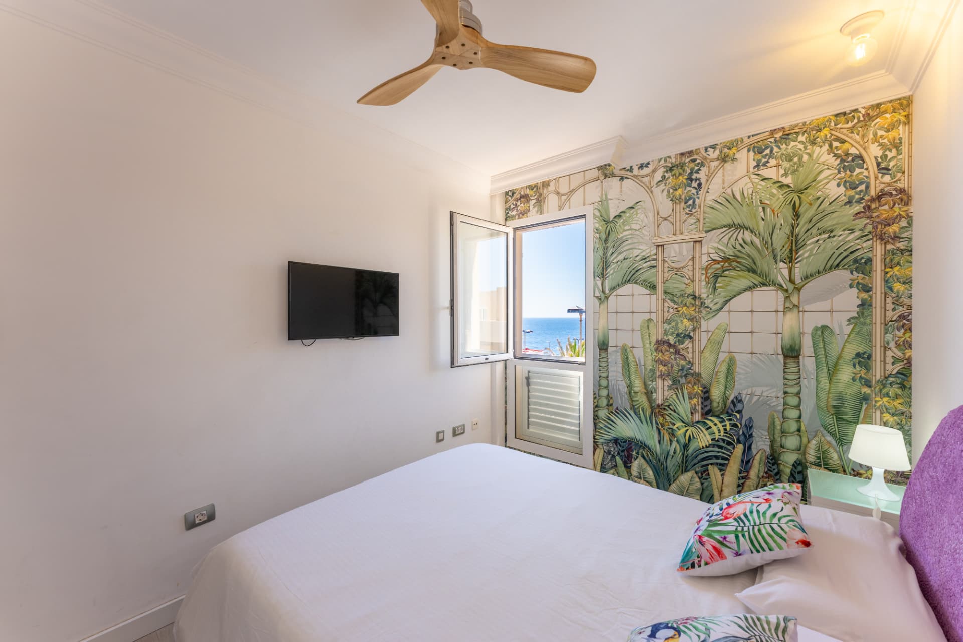 Dormitorio con vistas al mar y mural tropical